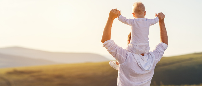 Man with small boy sitting on his shoulders, overlooking a view