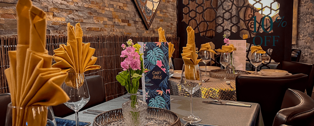 Chaat House table setting with turquoise menu, pink flower and