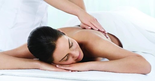lady laying down on her front with another lady laying her hands on her back.